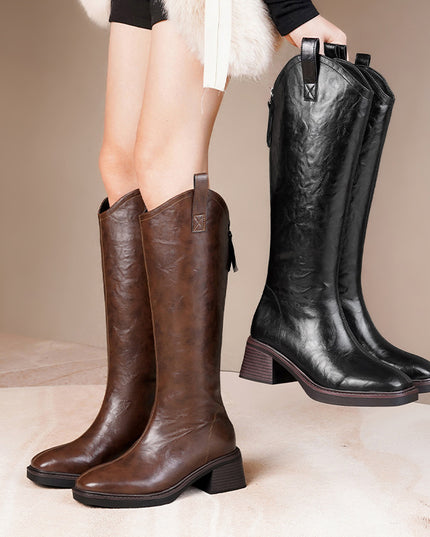 Brown and black knee-high boots on a neutral background