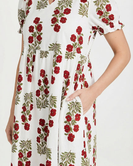 Woman wearing a white dress with red floral pattern on a white background