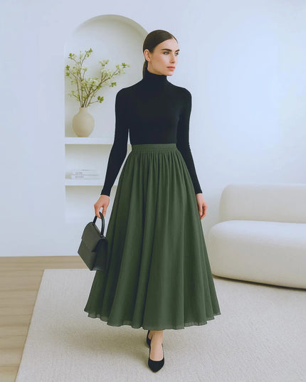 Woman wearing a black turtleneck and green skirt in a minimalistic room.