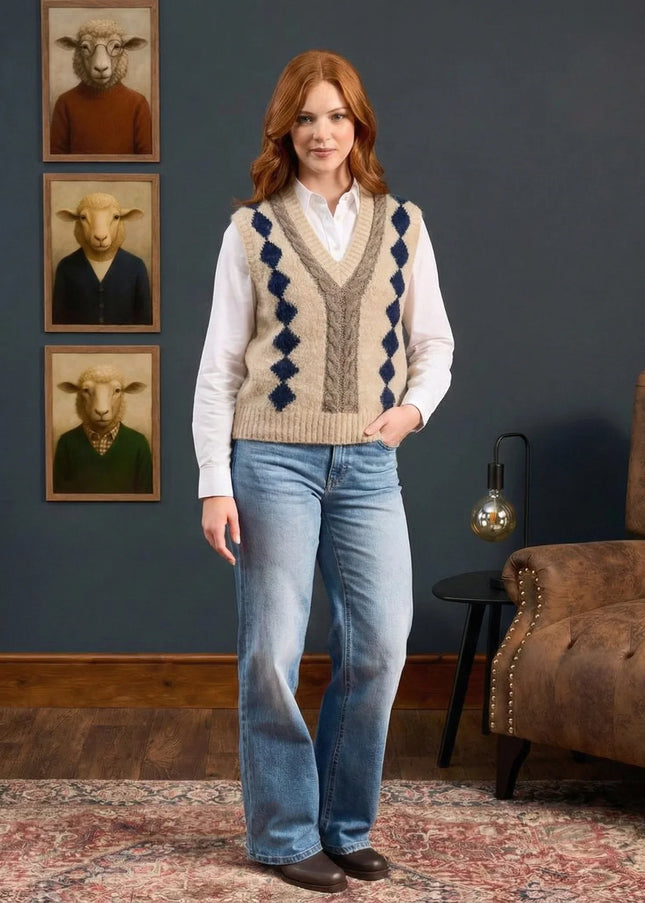 Woman wearing a patterned vest and jeans standing in a room with a brown armchair and wall art.