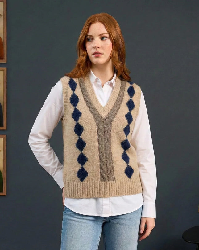 Woman wearing a patterned sweater vest with framed animal portraits on a dark wall.