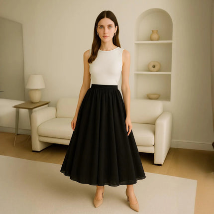 Woman wearing a white top and black skirt in a minimalistic living room.