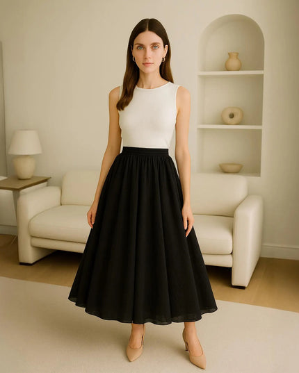 Woman wearing a white top and black skirt in a minimalistic living room.