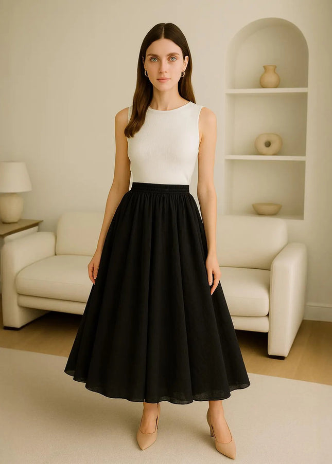 Woman wearing a white top and black skirt in a minimalistic living room.