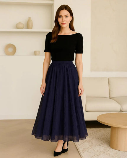 Woman wearing a black top and navy skirt in a living room setting