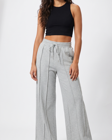 Woman wearing a black top and gray wide-leg pants on a white background