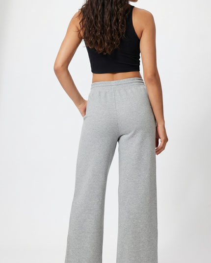 Woman wearing a black crop top and gray wide-leg pants on a white background