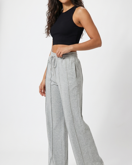 Woman wearing a black crop top and gray wide-leg pants on a white background