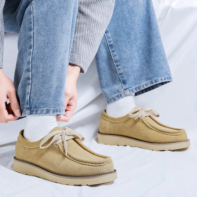 Beige loafers worn with blue jeans on a white background