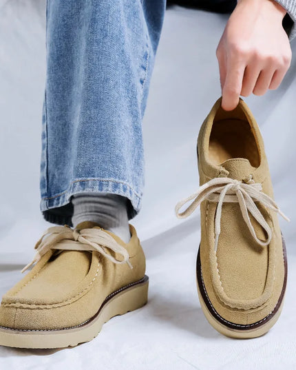 Beige loafers worn with blue jeans on a white background
