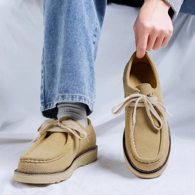 Beige loafers worn with blue jeans on a white background