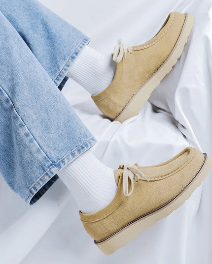 Beige loafers worn with light blue jeans and white socks on a white background