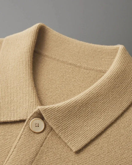 Close-up of a beige knitted polo shirt collar with a button on a gray background