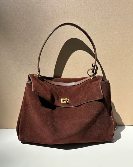 Brown suede handbag with a gold clasp on a beige background