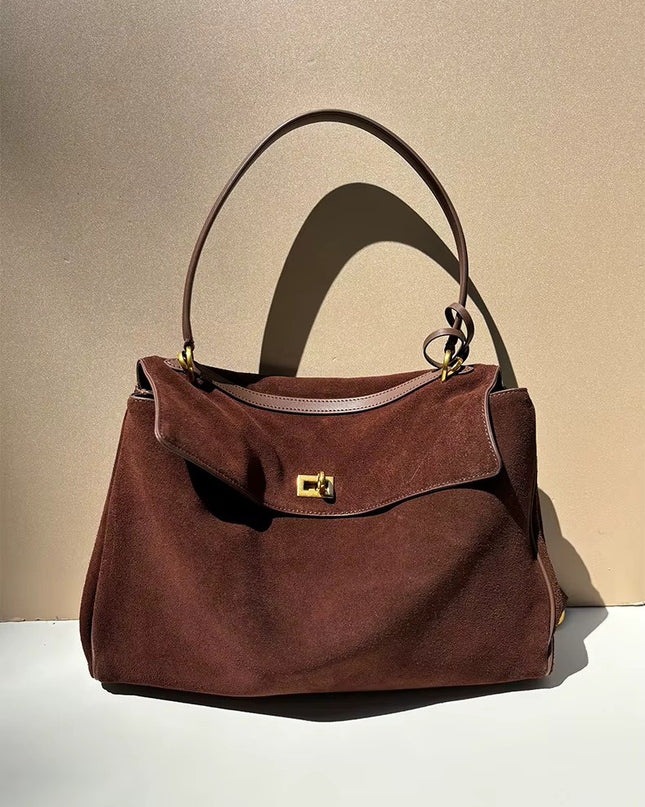 Brown suede handbag with a gold clasp on a beige background