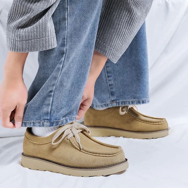 Beige shoes worn with blue jeans on a light gray background
