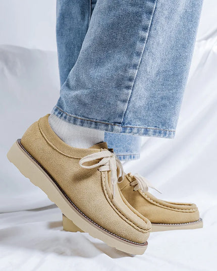 Beige shoes with white laces worn with light blue jeans on a white background