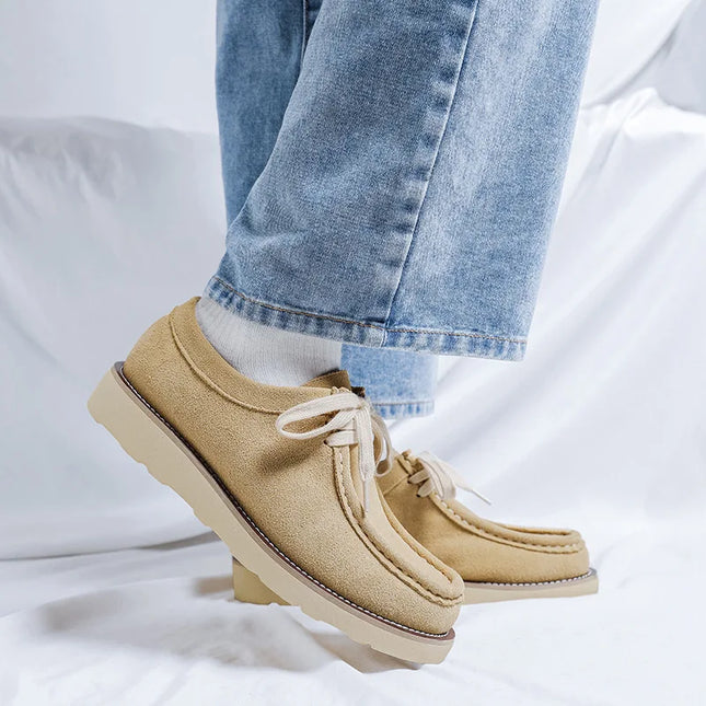 Beige shoes with white laces worn with light blue jeans on a white background