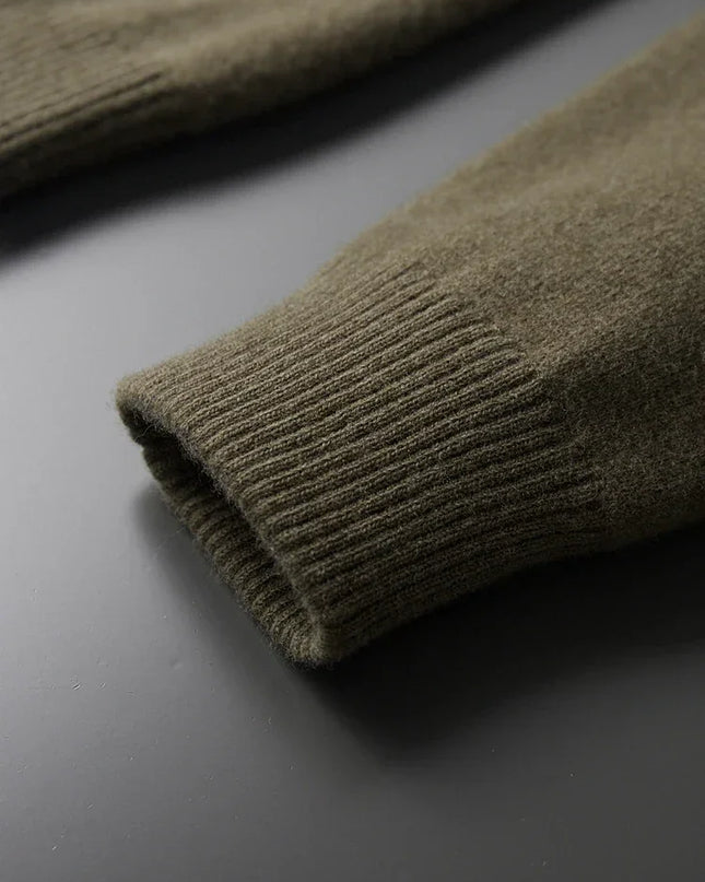 Rolled-up green sweater sleeve on a dark surface