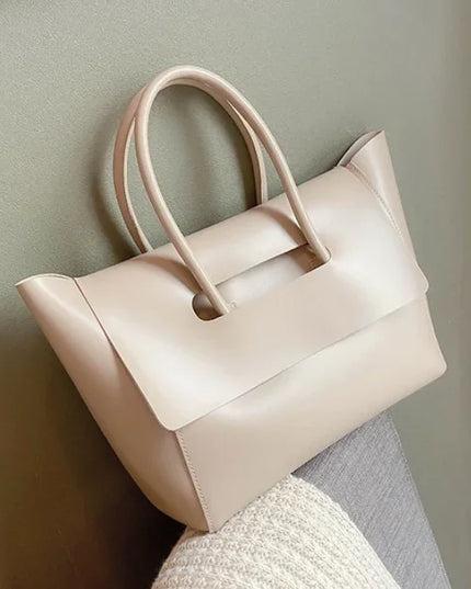 Beige handbag on a light gray surface with a neutral background