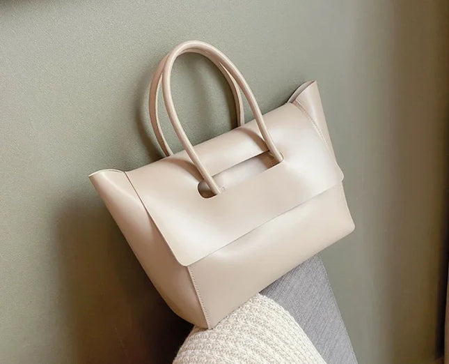 Beige handbag on a light gray surface with a neutral background
