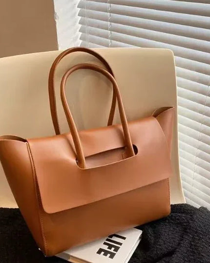 Brown leather handbag on a chair with a blurred background