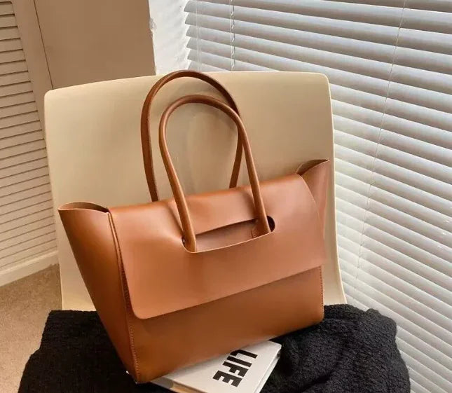 Brown leather handbag on a chair with a blurred background