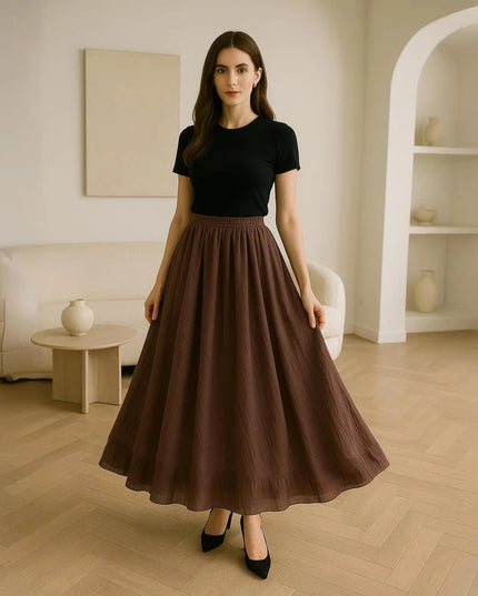 Woman wearing a black top and brown skirt in a modern living room.