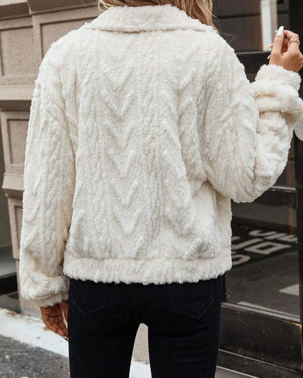 Person wearing a white cable knit sweater outdoors