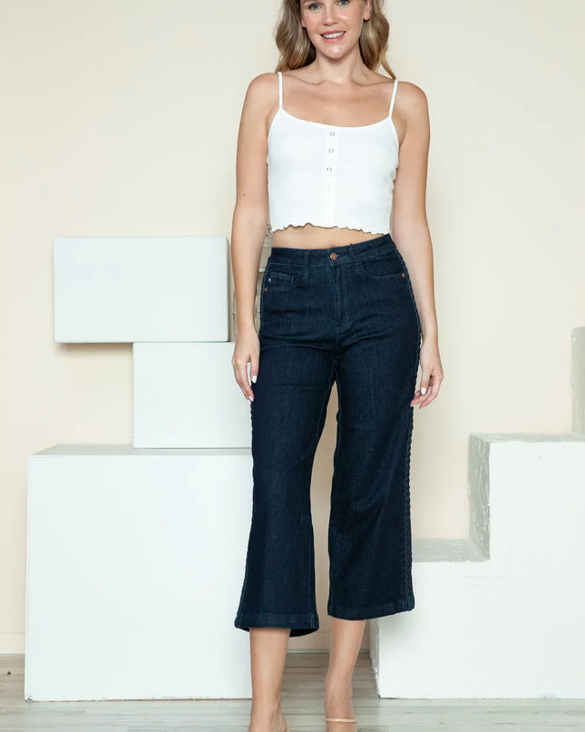 Woman wearing a white top and dark blue jeans standing on white steps.