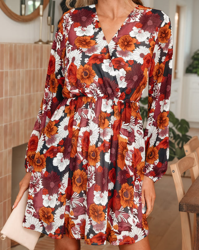 Woman wearing a floral dress with a pattern of red, orange, and white flowers indoors.