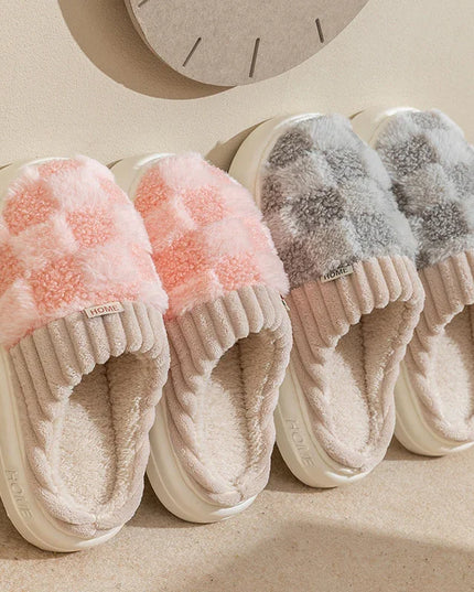 Pair of pink fuzzy slippers and gray fuzzy slippers on a beige surface.