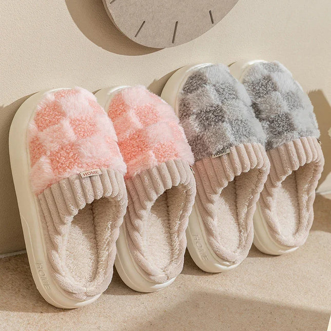 Pair of pink fuzzy slippers and gray fuzzy slippers on a beige surface.