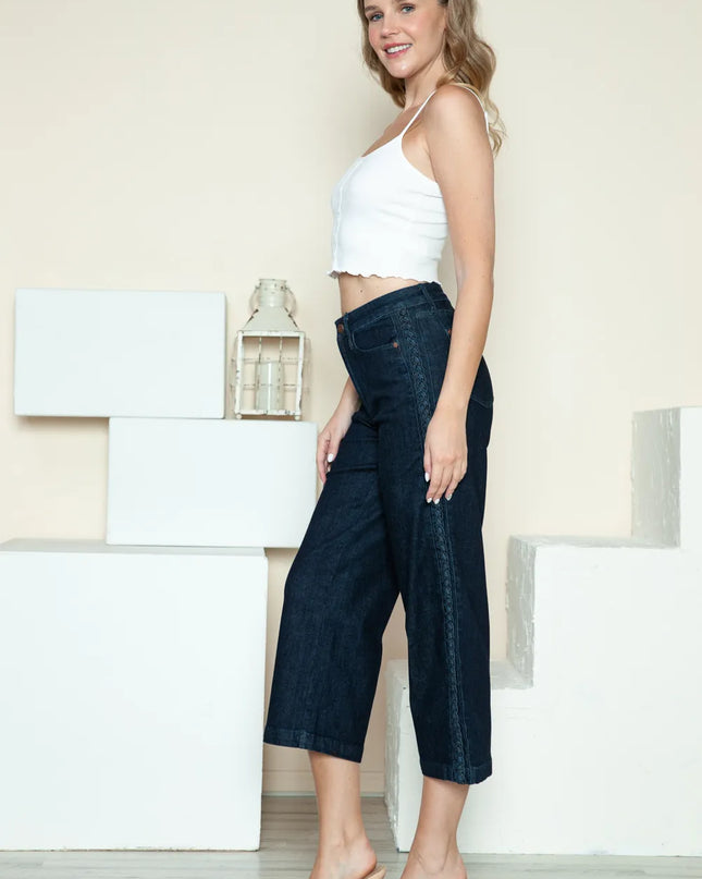 Woman wearing a white top and dark blue wide-leg pants standing indoors.