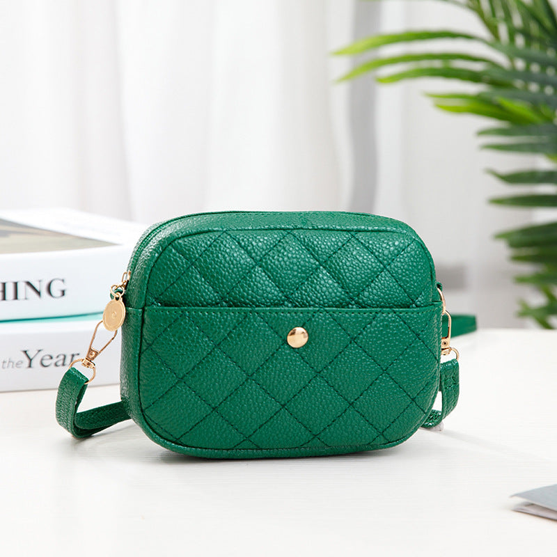 Green quilted handbag on a white surface with a plant in the background