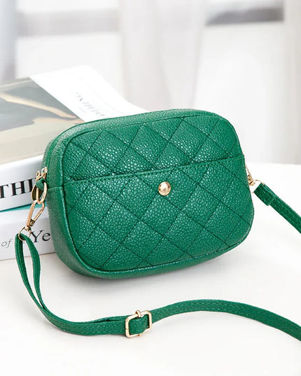 Green quilted handbag with gold accents on a white surface