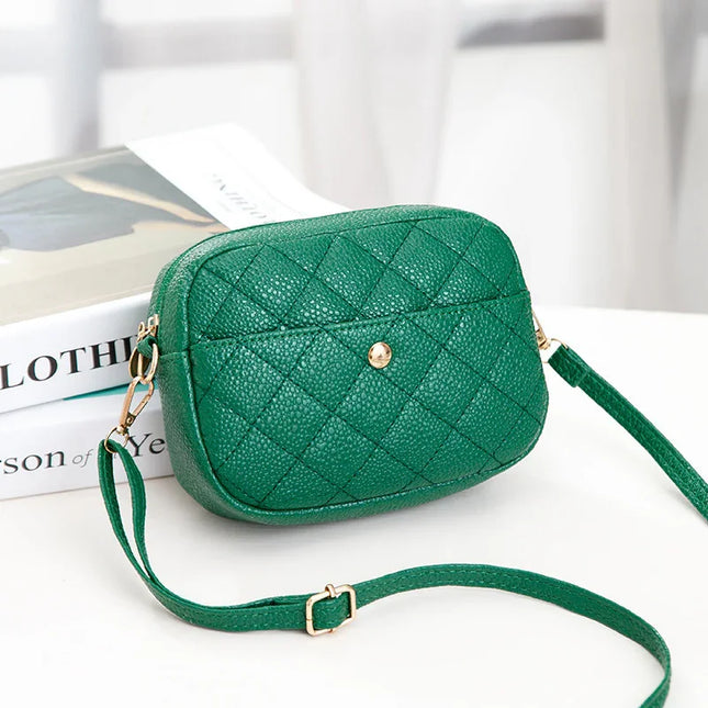 Green quilted handbag with gold accents on a white surface