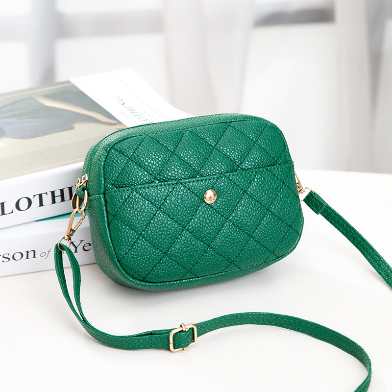 Green quilted handbag with gold accents on a white surface