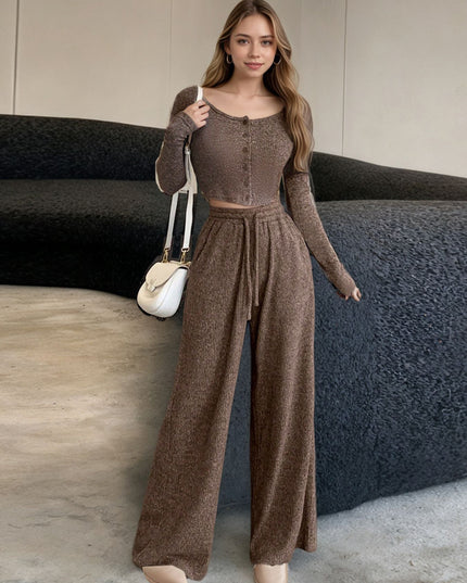 Woman wearing a brown outfit standing in a room with a dark sofa.