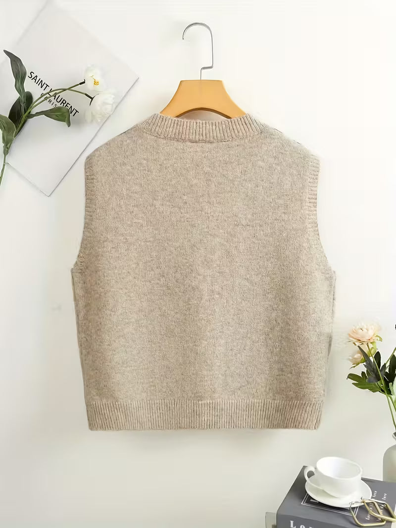 Beige sweater vest on a wooden hanger against a white background with decorative elements.