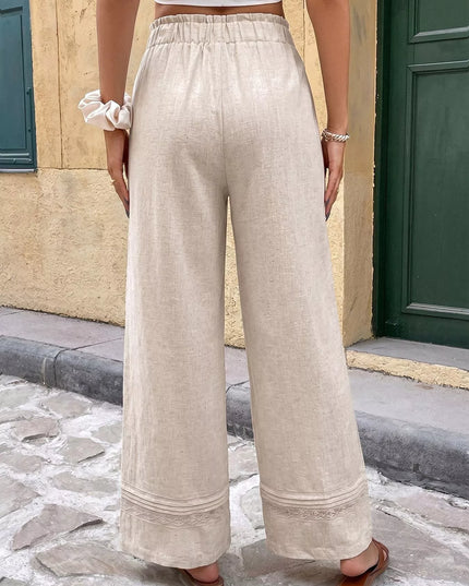 Person wearing beige wide-leg pants standing on a stone pavement.