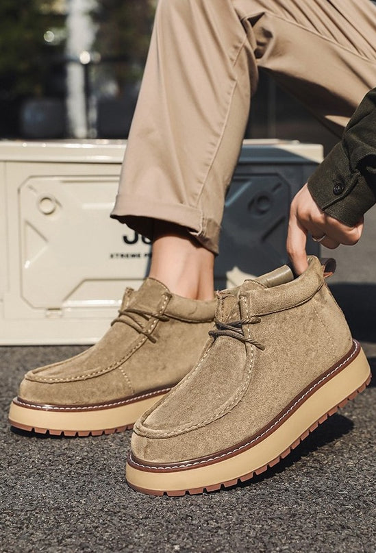 Brown suede shoes worn with beige pants on a dark surface
