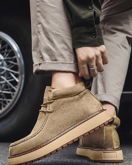 Person wearing brown suede boots with a car tire in the background