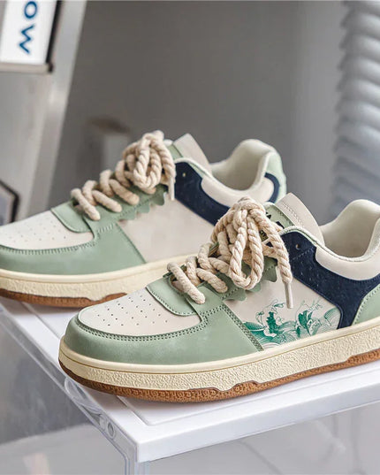 Pair of green and navy sneakers with white laces on a white surface.