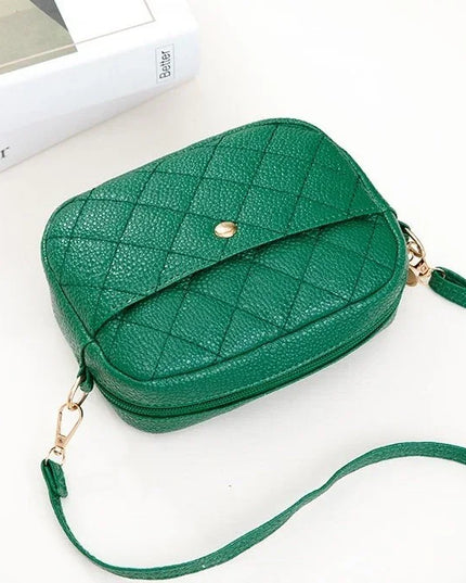 Green quilted handbag with a strap on a white background