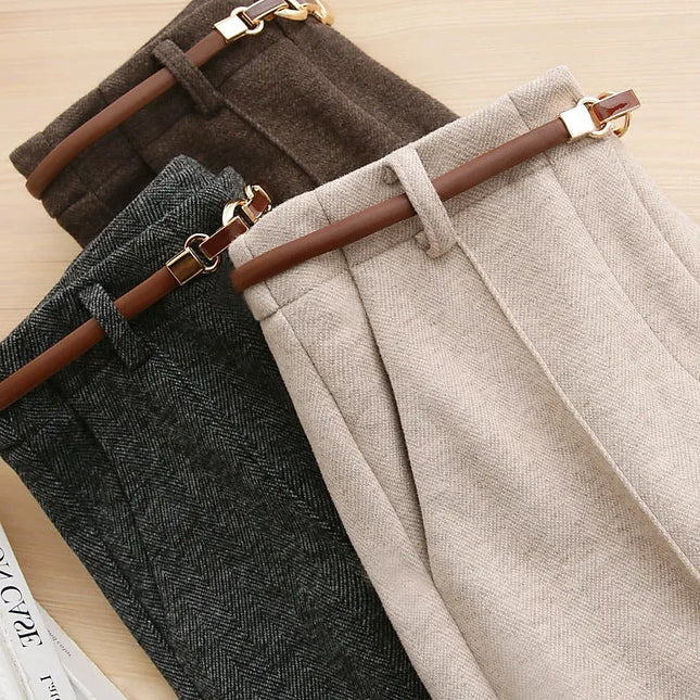 Three pairs of pants in brown, gray, and beige with brown belts on a light wooden surface.