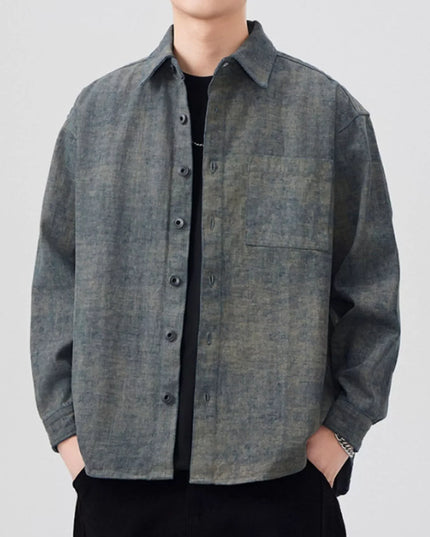 Person wearing a gray button-up shirt with a plain background