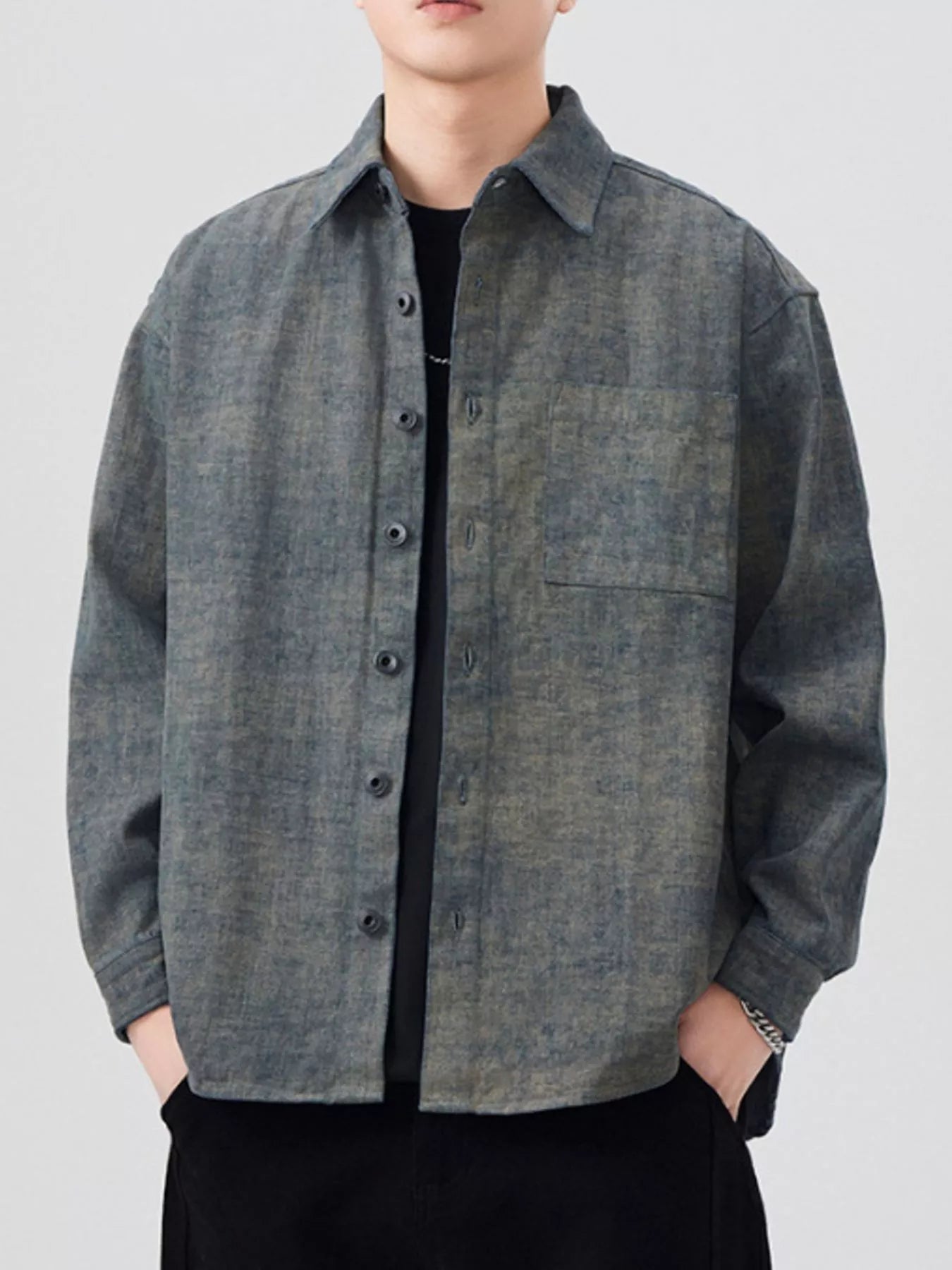 Person wearing a gray button-up shirt with a plain background