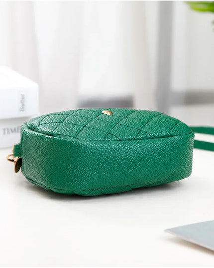 Green quilted handbag on a white surface with a blurred background