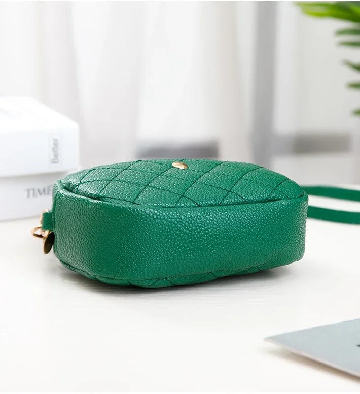 Green quilted handbag on a white surface with a blurred background